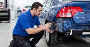 Technician inspectiong bumper-Auto Collision repair Lorens Body Shop